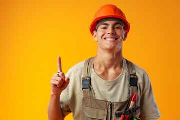 Wall Mural - Young construction worker in uniform posing on yellow background in studio