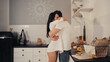 © LIGHTFIELD STUDIOS - brunette young woman in white shirt hugging boyfriend in modern kitchen.