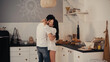 © LIGHTFIELD STUDIOS - happy woman in white shirt embracing boyfriend in modern kitchen.