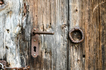 Old Door Handle, Close Up. Ancient Rusty Door Handle And Keylock On Brown Old Wooden Door. House Gate.