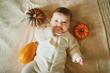 adorable baby lying on blanket, playing with mini pumpkin