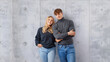 © Igor Link - Portrait of young smiling people guy and girl 20s in basic clothing posing together at camera with happy look, isolated over concrete gray wall indoor