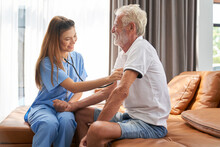 Smiling Nurse Is Checking Up For Good Health To Oldy Patient On Sofa In House , Home Healthcare Service