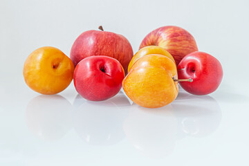 Wall Mural - sweet ripe juicy plums and red apples on white glass surface