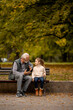 © BGStock72 - Grandfather spending time with his granddaughter on bench in park on autumn day