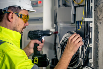 Wall Mural - Man, an electrical technician working in a switchboard with fuses.