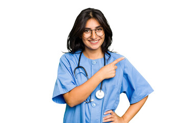 Wall Mural - Young nurse Indian woman isolated smiling and pointing aside, showing something at blank space.