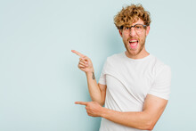 Young Caucasian Man Isolated On Blue Background Pointing With Forefingers To A Copy Space, Expressing Excitement And Desire.