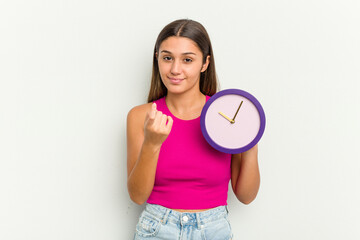 Young Indian woman holding a clock isolated on white background pointing with finger at you as if inviting come closer.