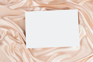 Wall Mural - Mock up blank white board canvas poster card for text on draped beige satin silk fabric cloth background. Top view