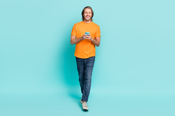 Sticker - Full length photo of cheerful attractive guy dressed orange t-shirt communicating modern device isolated teal color background