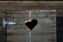 Outdoor Wooden Toilet Door Fragment With Cut Heart Symbol And Metal Hinge