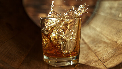 Wall Mural - Ice cube falling into glass of whisky in wooden barrel.