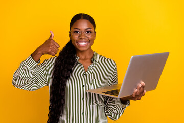 portrait of beautiful attractive girl hold netbook hand finger show thumb up isolated on yellow colo