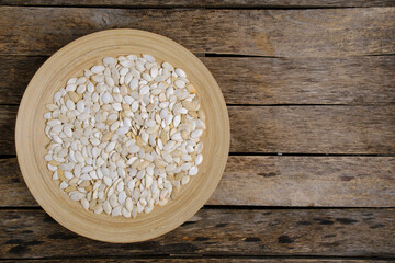 Wall Mural - Pumpkin seeds in wooden plate on wooden background.