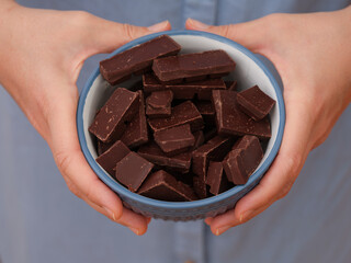 Wall Mural - A woman holding a bowl of broken dark chocolate in her hands