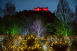 View of Princes Street Gardens with Christmas decorated trees and a colourful light display in Scotland, Uk, with an illuminated Edinburgh Castle on the background during Christmas time