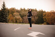 © finwal89 - Beautiful young woman looking away while standing on the road against trees during autumn