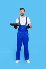 Poster - Professional worker with putty knife on light blue background