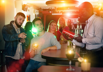 Wall Mural - Portrait of male bartender shaking cocktail mixer for men in nightclub