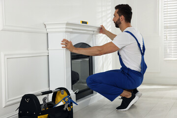 Sticker - Professional technician using construction level for installing electric fireplace in room