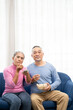 © Wongsakorn - Happy smiling asian senior couple sitting on sofa and watching TV at home in living room. senior spending weekend time together.