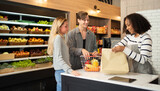 Fototapeta Tulipany - A caucasian couple shopping in a supermarket or retail shop, buying snacks and food in cashier on grocery products shelves with a basket. Food shopping. People lifestyle.  Checkout service