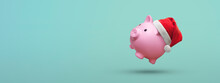 Pink Piggy Bank With Santa Claus Hat On A Blue Background - Saving Concept For Christmas
