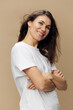 © Tatiana - portrait of a cute, happy, beautiful brunette woman, with hair blowing in the wind, in a white tank top, standing sideways with her arms crossed on her chest, and smiling at the camera