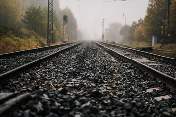 Railroad track rails in coutry landspace in autumn weather with foggy landscape. Industrial concept. Railroad travel, railway tourism.