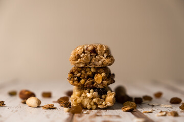 Various energy bars with granola chocolate in a row with scattered nuts, cereals and dried fruits, a grunge background of a white wood table. A healthy vegan snack for fitness. Close-up.