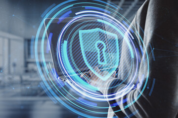 Canvas Print - Close up of hacker hand using laptop with glowing shield hologram on blurry office interior background. Secure, data theft, malware, safety and web protection concept. Double exposure.