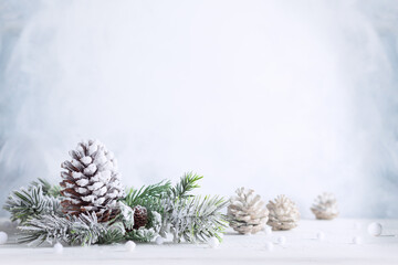 Wall Mural - christmas still life with snowy pine cones, baubles and fir branches on light background. winter or 