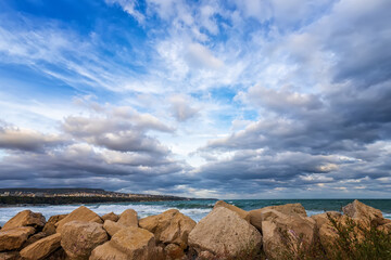 Wall Mural - Dramatic clouds over the sea and big rocks at the shore