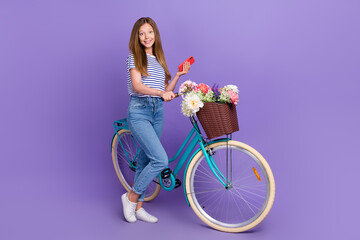 Poster - Full length photo of funny sweet small schoolgirl wear striped t-shirt typing modern device riding bicycle isolated purple color background