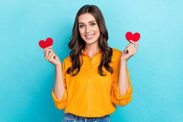 Sticker - Portrait of adorable positive lady arms hold small red paper heart symbols isolated on blue color background