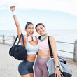 Excited, fitness success and friends exercise by ocean for outdoor training wellness, accountability and happy with body results. Happy sports women with workout bag and headphones for motivation