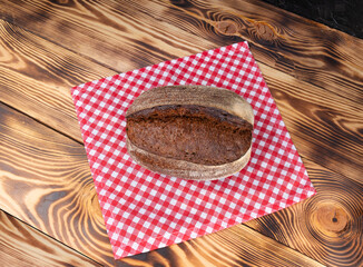 Wall Mural - Brown bread fresh on a bright napkin on a wooden table