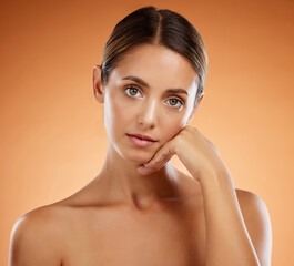 Sticker - Skincare, beauty and portrait with hand pose and serious face of beautiful woman with glowing body. Model girl at orange background with natural, young and cosmetic feeling on skin in studio.