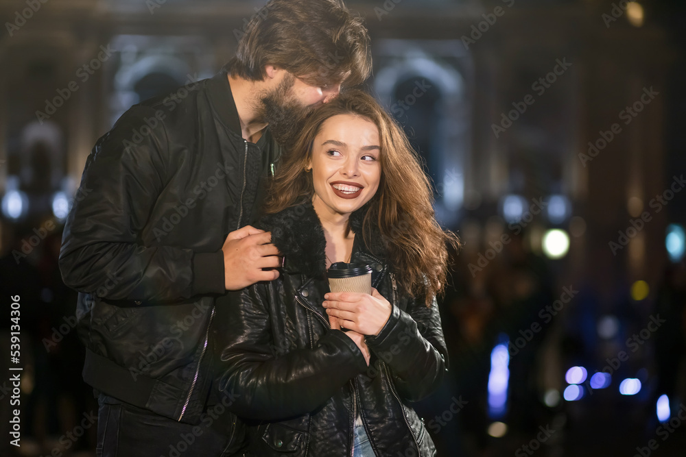Smiling man and woman in love enjoying an evening walk together. They drink coffee