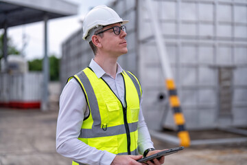 Wall Mural - Engineer working at power station plant standing portrait play tablet PC while waiting manager to visit