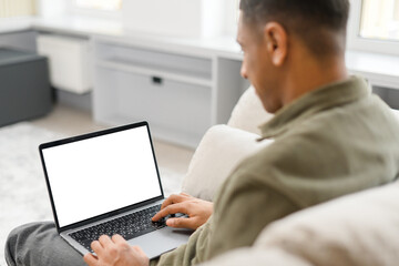 Photo over the shoulder of the man sitting in front of laptop and looking at something on the screen, choosing, viewing, texting, listening to lecture, using new modern fast communication app