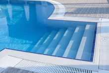 Fiberglass Plastic Swimming Pool Entrance Step With Clean Blue Water At Resort Hotel Spa Area. Convenient Access To The Pool For Children And The Elderly.