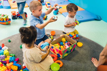 Wall Mural - 'look, what I have' - little boy holding toys in his hands and showing them to his teacher. High quality photo