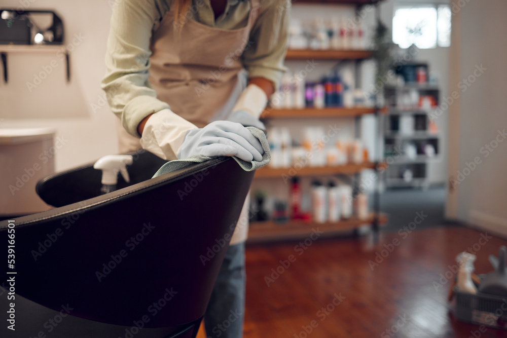 Salon, small business and woman cleaning chair with equipment in modern beauty parlor in city. Cleaner, maid or girl washing furniture at hairdressing shop with hygiene and sanitizing products.