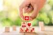 © Puttachat - Hand arranged wooden blocks with icons of medical health. health insurance for your health concept. Healthcare medical business, medical technology equipment icon, health care protection concept.