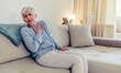 © Jelena Stanojkovic - Photo of senior woman suffering from chest pain while sitting on sofa at home during the day. Old age, health problem and people concept - close up of senior woman suffering from heartache at home.