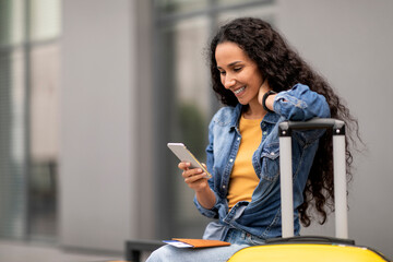 Wall Mural - Happy lady travelling alone, using smartphone while waiting for boarding