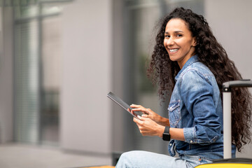 Wall Mural - Happy young woman waiting for flight, using digital tablet