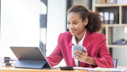 Smiling young African american female Finance Entrepreneur sitting in workplace office hoding coffee cup and working on a laptop, investment financial document report finance analysis concept.